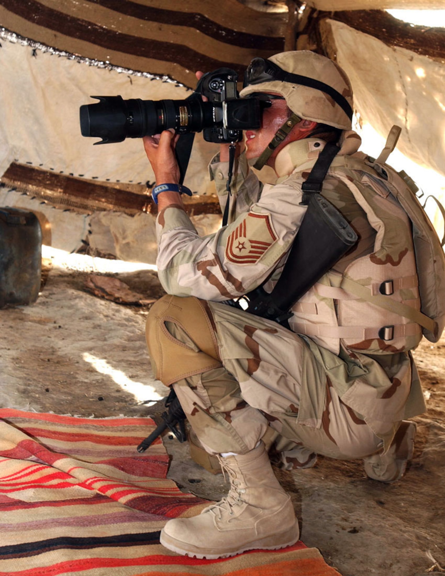 IRAQ -- Master Sgt. Maurice Hessel photographs a security forces mission in the local area outside Ali Base's perimeter.  Base photographers document the Air Force mission during peace and war.  He is the 407th Expeditionary Communications Squadron base multimedia center manager.  (U.S. Air Force photo by Airman 1st Class Jamie Shultz)