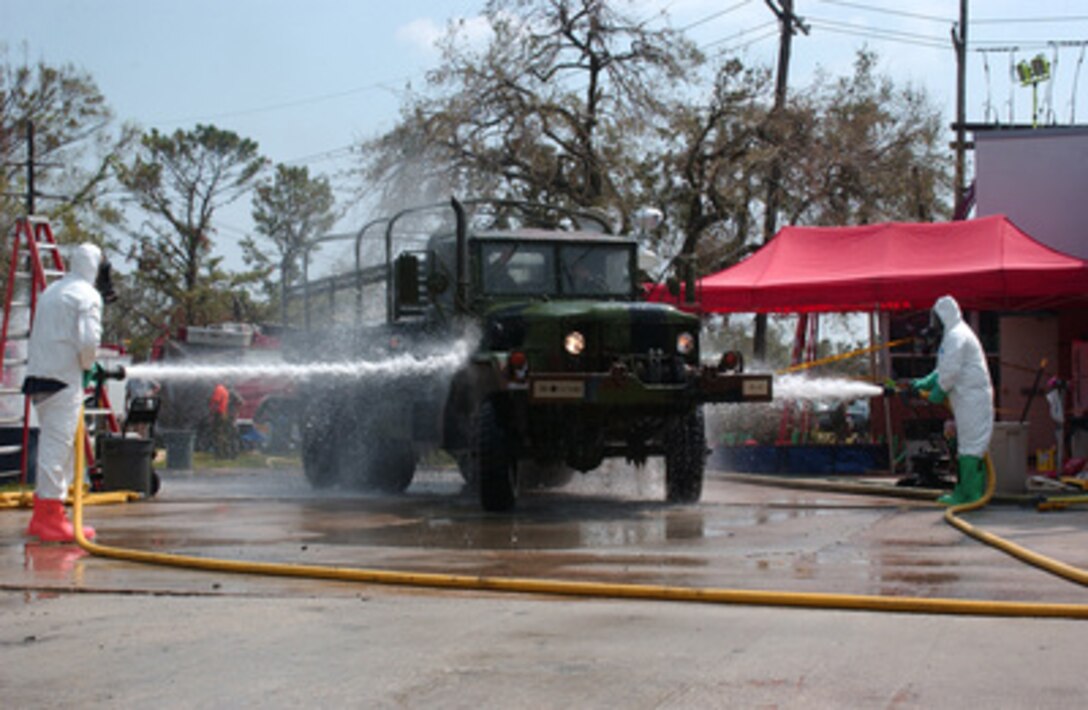 A military vehicle is washed with fire hoses as it passes through a decontamination station at a fire department in New Orleans, La., on Sept. 14, 2005. All military and civilian service vehicles are brought to the station after returning from potentially contaminated areas. The vehicle belongs to 4th Battalion, 133rd Field Artillery, Task Force San Antonio, which is a combined force of Air and Army National Guard units deployed to New Orleans. Department of Defense units are mobilized as part of Joint Task Force Katrina to support the Federal Emergency Management Agency's disaster-relief efforts in the Gulf Coast areas devastated by Hurricane Katrina. 