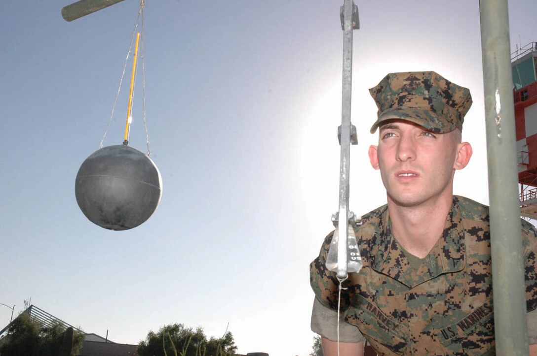 ) Lance Cpl. Ryan Harvey, Headquarters and Headquarters Squadron weather observer and native of Refugio, Texas, takes the temperature from a thermometer attached to a water-soaked wick Sept. 23 in front of the Station Meteorological Oceanographic Command. The temperature reading from this thermometer is one of three numbers used to determine which physical training safety flag is flown on station. Station METOC Marines check these readings every hour to make sure those exercising on station are well informed throughout the day, as well as using the data to more accurately predict the weather.