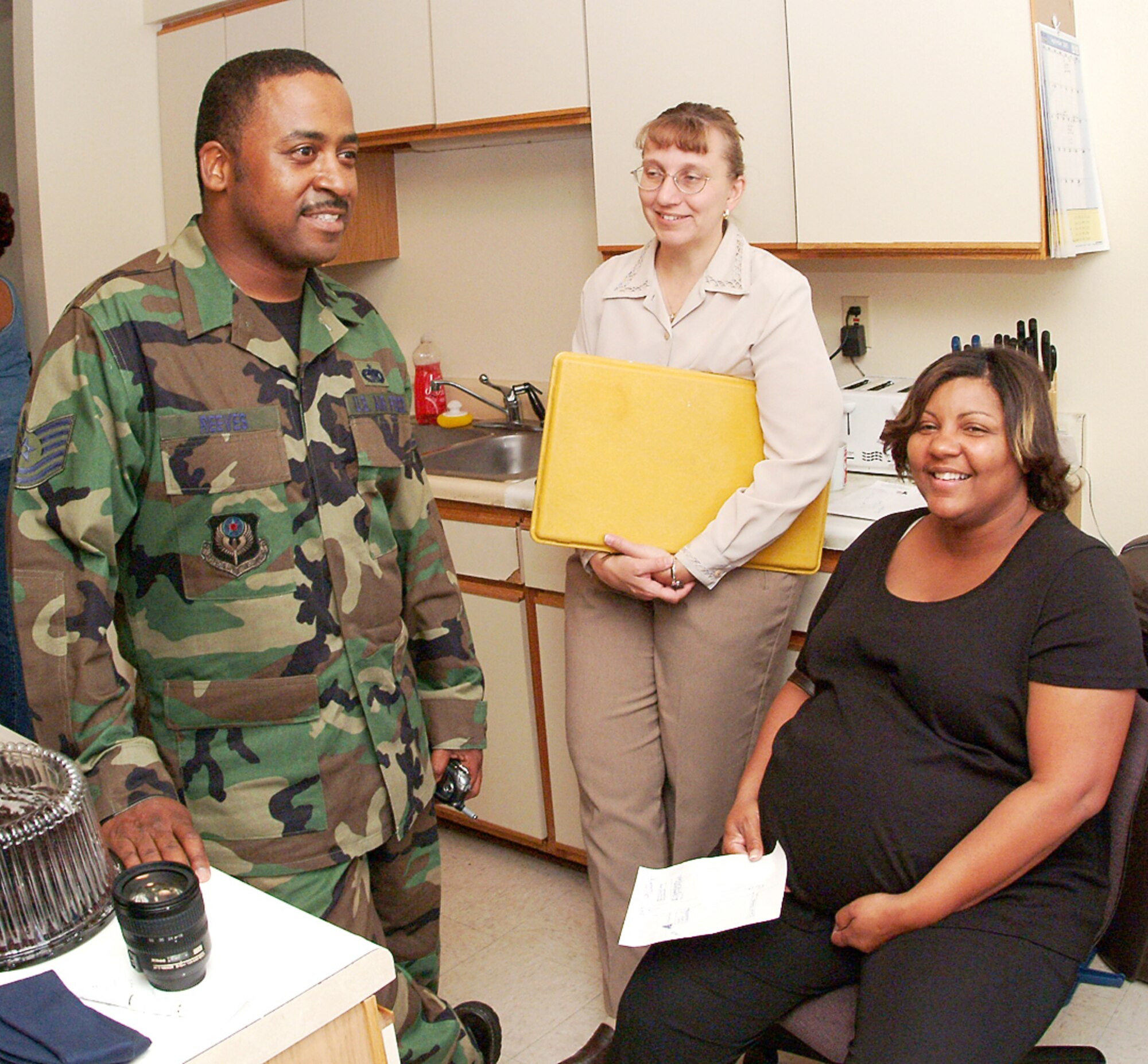 HURLBURT FIELD, Fla. -- Tech. Sgt. Christopher Reeves, his wife Donnice and Kathy Thompson (center) share a moment in the kitchen of the Reeves' home.  Mrs. Thompson and a crew from the 53rd Wing at nearby Eglin Air Force Base had just dropped off dinner for the family of 22 who escaped Hurricane Katrina to stay here with the Reeves.  Sergeant Reeves is assigned to the 16th Logistics Readiness Squadron here.  (U.S. Air Force photo by Master Sgt. Tonya Keebaugh)