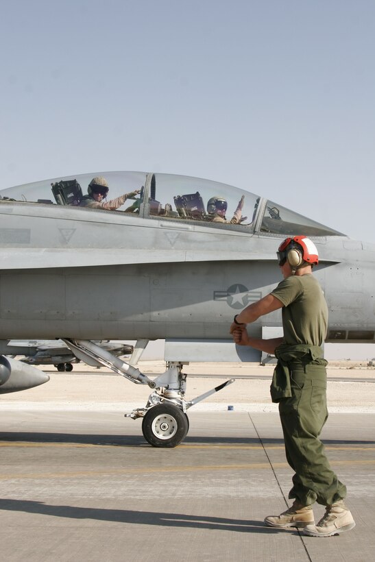 AL ASAD, Iraq - Sergeant Travis G. Poitras, an ordnanceman with Marine All-Weather Fighter Attack Squadron 332 and Limington, Maine, native, signals pilots to keep their hands off the controls while Marines arm ordnance loaded onto one of the Moonlighters? F/A-18 Hornets, Sept. 21, at Al Asad, Iraq.