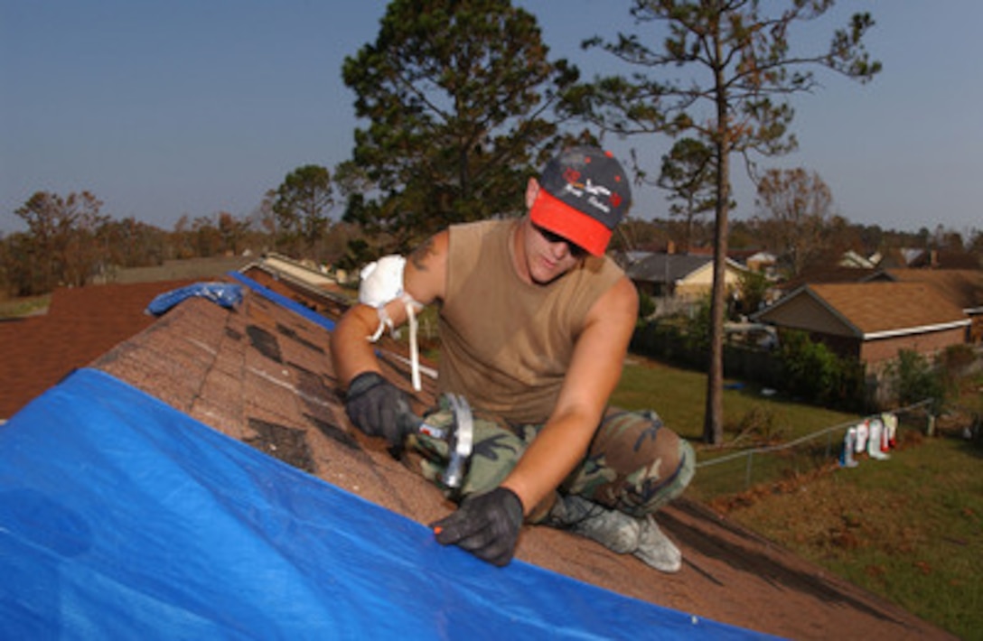Air Force Senior Airman Gene Keller nails a covering on the roof of a home damaged by Hurricane Katrina in Biloxi, Miss., on Sept. 14, 2005. Keller is attached to the 119th Fighter Wing of the North Dakota Air National Guard. Department of Defense units are mobilized as part of Joint Task Force Katrina to support the Federal Emergency Management Agency's disaster-relief efforts in the Gulf Coast areas devastated by Hurricane Katrina. 