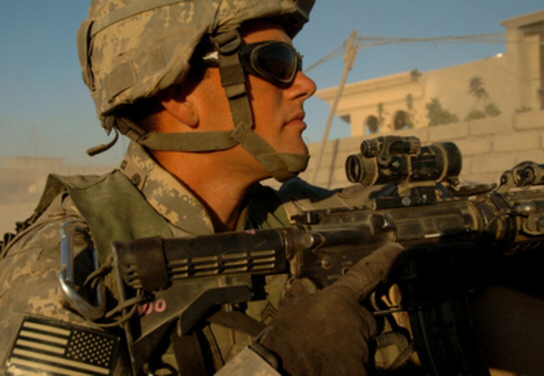 A U.S. Army infantryman scans nearby buildings during a convoy in