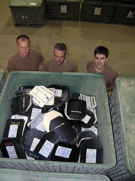 ALI BASE, Iraq -- (From left) Senior Airman Josh Warren, Master Sgt. Steve Strange and Senior Airman Caslon Smith stand by a crate holding damaged body armor plates.  Much of the armor is unusable because it was mishandled.  The Airmen are assigned to the 407th Expeditionary Logistics Readiness Squadron here.  (U.S. Air Force photo by Tech. Sgt. Paul Dean)       