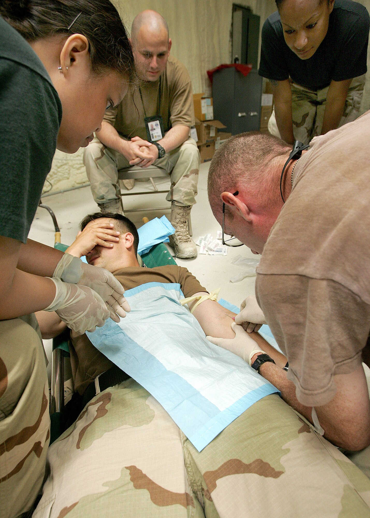 CAMP BULLIS, Texas -- Staff Sgt. Becky Braley (left) watches Tech. Sgt. William Byrd (right) insert an IV into Tech. Sgt. Brian Pederson's arm during the Basic Combat Convoy Course combat lifesaver training.  Sergeant Braley is a course instructor and medic from Seymour Johnson Air Force Base, N.C.  Sergeant Byrd is from Scott AFB, Ill., and Sergeant Pederson is from Dover AFB, Del.  (U.S. Air Force photo by Robbin Cresswell)