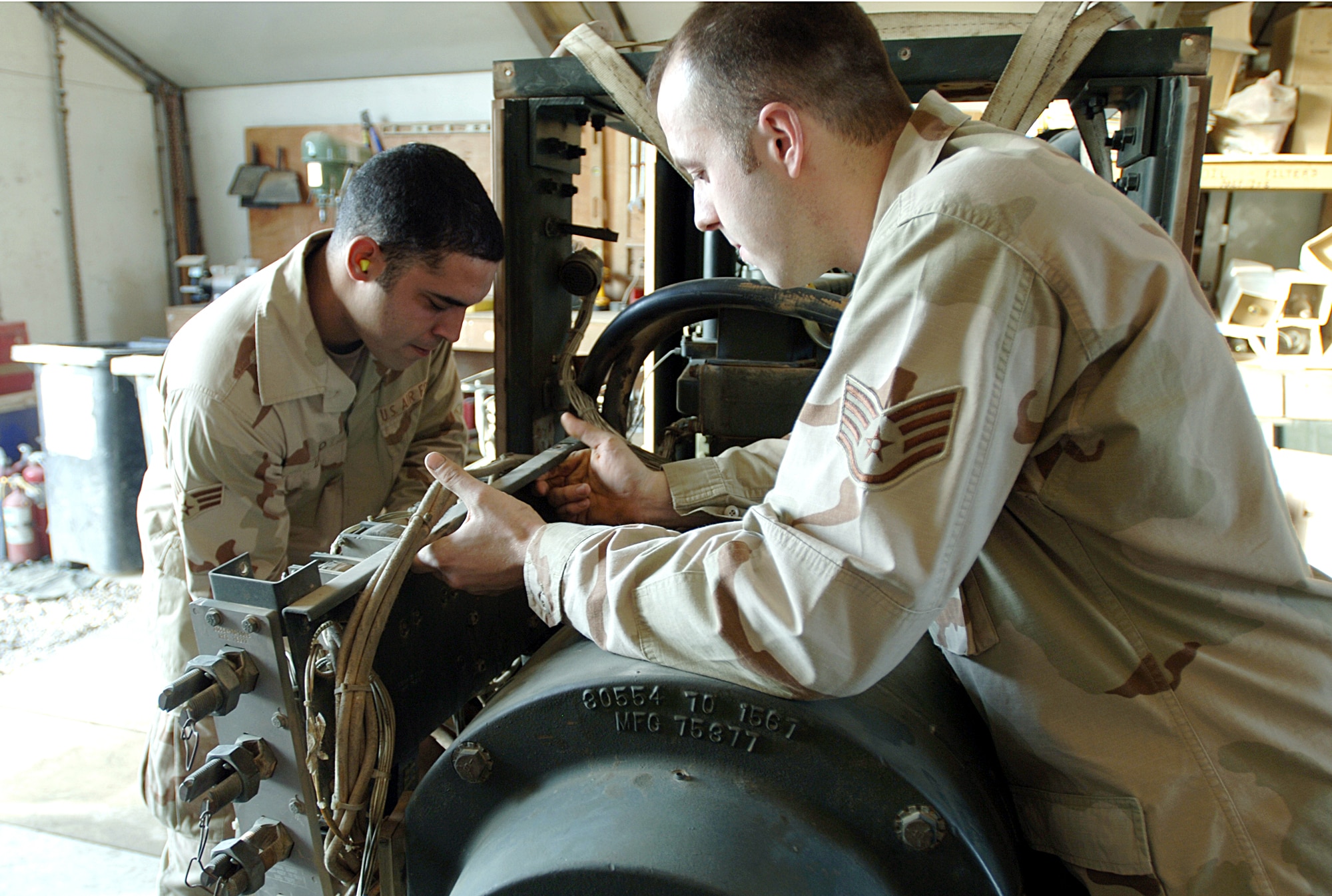 ALI BASE, Iraq -- Senior Airman Jamie Lugo (left) and Staff Sgt. Chad Poeth change the alternator on a generator here. They are assigned to the 407th Expeditionary Civil Engineer Squadron power production element. (U.S. Air Force photo by Master Sgt. Maurice Hessel)
