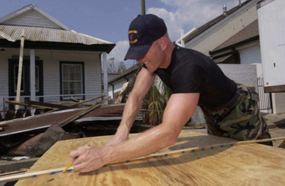 Senior Airman Martin Whalen of the 110th Civil Engineering Squadron, Battle Creek, Mich., prepares to cut a sheet of plywood to repair the roof of the Hancock County Historical Society building in Bay St. Louis, Miss., on Sept. 20, 2005. Department of Defense units are mobilized as part of Joint Task Force Katrina to support the Federal Emergency Management Agency's disaster-relief efforts in the Gulf Coast areas devastated by Hurricane Katrina. 