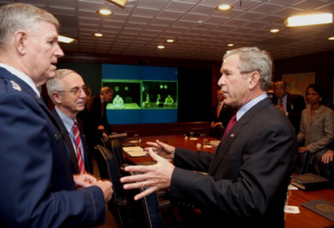 President George W. Bush (right) talks with Chairman of the Joint Chiefs of Staff Gen. Richard B. Myers, U.S. Air Force, (left) and Acting Deputy Secretary of Defense Gordon England (2nd from left) in the Pentagon on Sept. 22, 2005. Bush spoke to reporters after receiving a briefing. 