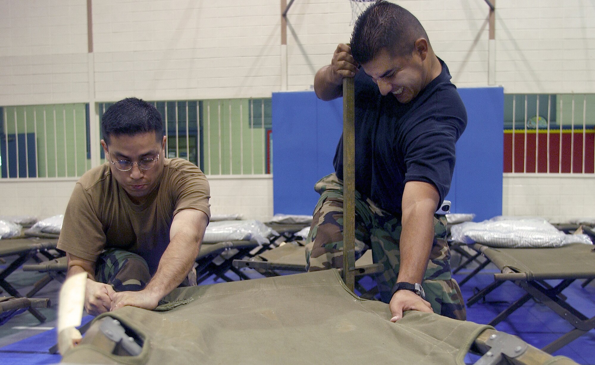 ABILENE, Texas -- Senior Airman Oscar Lamas and Staff Sgt. Jesus Ramirez assemble a cot Sept. 23 at an American Red Cross shelter here. About 100 Airmen from Dyess Air Force Base volunteered to prepare three shelters for more than 450 evacuees seeking refuge from Hurricane Rita. (U.S. Air Force photo by Airman 1st Class Chris Walkenhorst)       