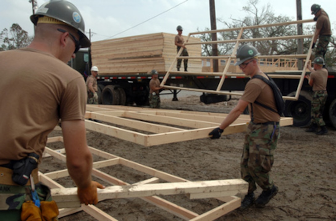 U.S. Navy Seabees assigned to Naval Mobile Construction Battalion 4 help assemble the foundation for the first of 75 temporary housing shelters in Pass Christian, Miss., on Sept. 24, 2005. The Seabees practice contingency construction projects like these shelters on a constant basis and can build as many as four in one day. Department of Defense units are mobilized as part of Joint Task Force Katrina to support the Federal Emergency Management Agency's disaster-relief efforts in the Gulf Coast areas devastated by Hurricane Katrina. 
