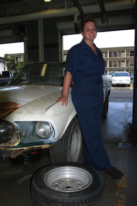 Michelle E. Wood stands beside one of her currrent passions, working on her 69 Ford Mustang convertible at the Auto Hobby Shop.