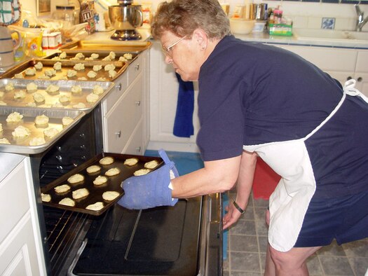 MCCONNELL AIR FORCE BASE, Kan. (AFPN) -- Merry Debbrecht, the "Rose Hill Cookie Lady," pulls another batch of fresh cookies out of her oven. To show her support to the American military, she bakes a minimum of 20 dozen cookies every day and sends them to deployed troops. Since February 2005, she has baked more than 30,000 cookies. (U.S. Air Force photo by Staff Sgt. Kristine Dreyer)          