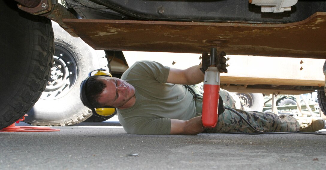 Staff Sgt. Pablo Torrez, maintenance chief of the 15th Marine Expeditionary Unit, and a native of Keller, Texas, removes class 2 armor from the bottom of a humvee in their motor pool at Camp Del Mar here. The 15th MEU removed their class 2 armor in preparation for installing MAK 1 armor.