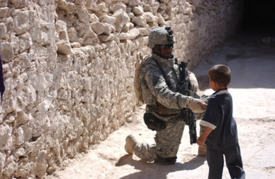 U.S. Army Spc. Nathan K. Edwards with Company A, 2nd Battalion, 82nd Airborne Division shakes the hand of an Iraqi boy during a cordon and search mission in Tall Afar, Iraq, on Sept 27, 2005. 
