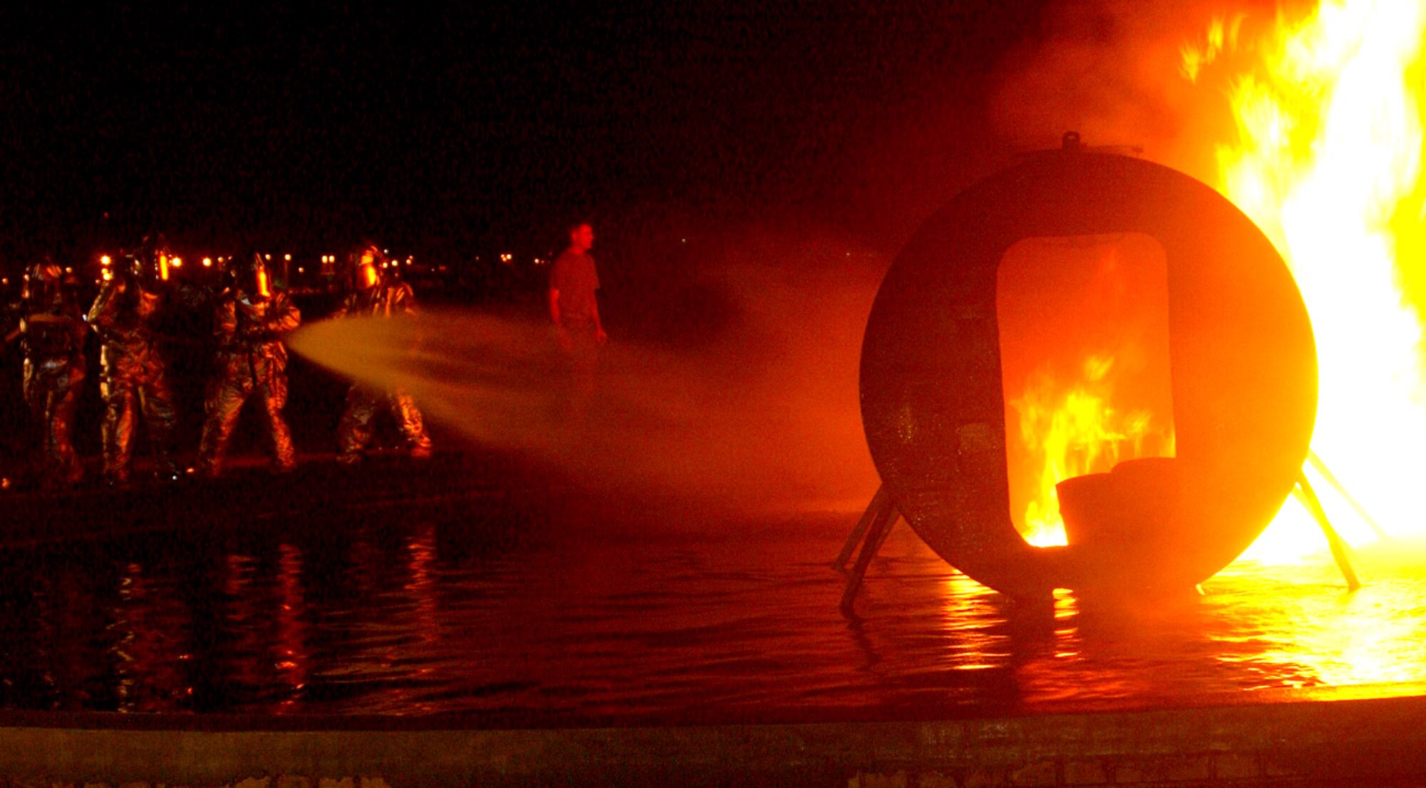 MARINE CORPS AIR STATION FUTENMA, Japan -- Kadena fire emergency services Airmen work together to extinguish a fire on a simulated crash at a fuel fire pit here Sept. 22.  The 18th Civil Engineer Squadron Airmen used the Marine facility for training while theirs is undergoing maintenance.  (U.S. Marine Corps photo by Pfc. Terence L. Yancey)