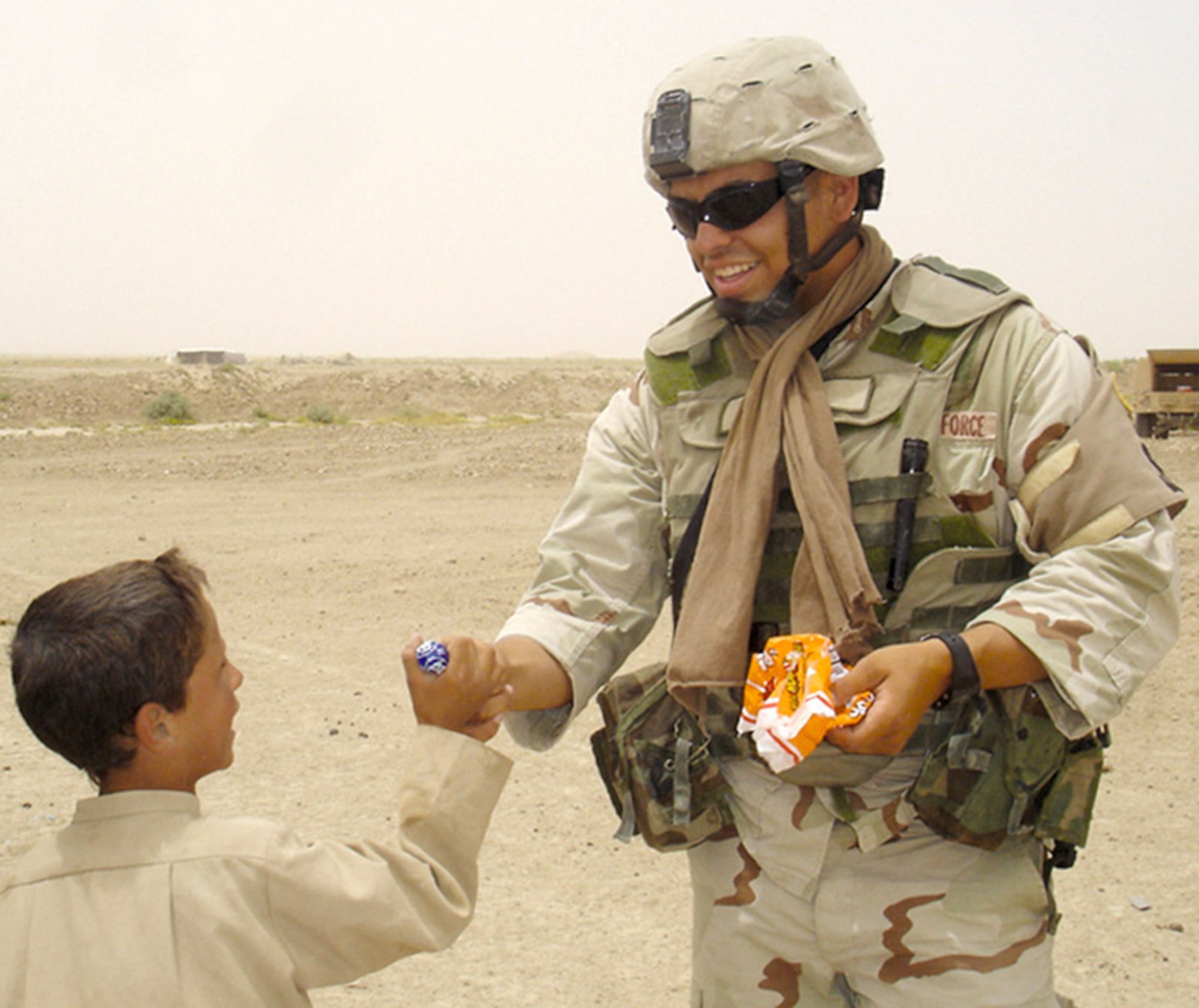 IRAQ -- Airman 1st Class Phillip Ovalle, pictured here handing out candy to an Iraqi child near Ali Base where he was deployed earlier this summer, was shot to death Sept. 27 while on post-deployment leave in Texas. Airman Ovalle was assigned to the 4th Security Forces Squadron at Seymour Johnson Air Force Base, N.C. (U.S. Air Force photo)