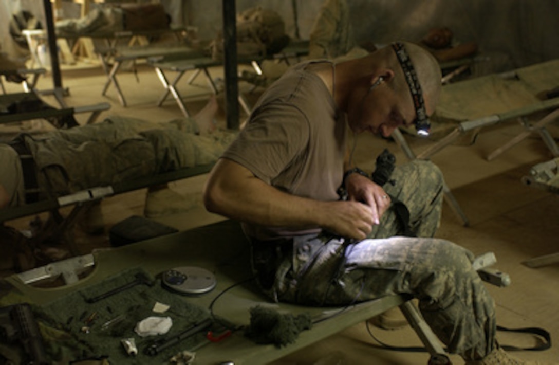 U.S. Army Spc. Sterling Peele cleans his weapon after a mission searching for weapons caches and insurgents in the town of Anah, Iraq, on Sept. 29, 2005. Peele is assigned to Headquarters Company, 172nd Stryker Brigade Combat Team. 