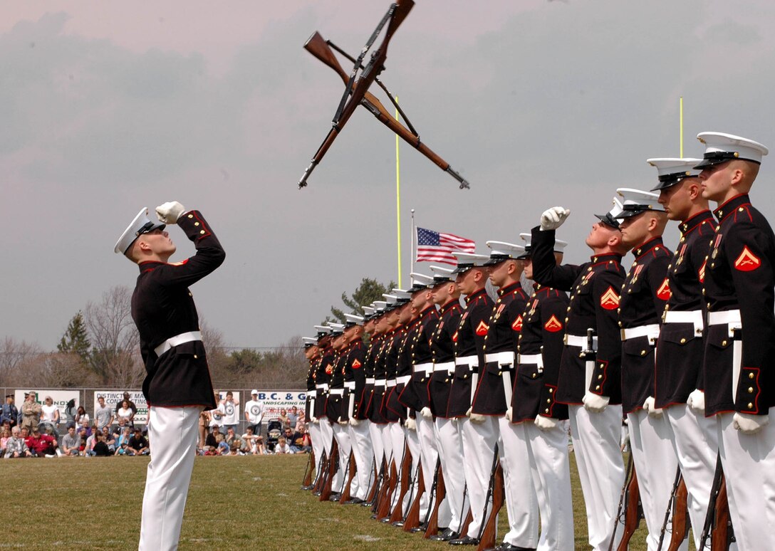 Members of the Silent Drill Platoon exchange rifles during a performance for the 3,000 spectators attending the inaugural Service to America Day at Colt?s Neck High School, April 1.  The event, co-hosted by Recruiting Station New Jersey, also featured the Quantico Marine Band, as well as static displays of Marine Corps vehicles and aircraft. The guest of honor was Lt. General James N. Mattis, commanding general of the U.S. Marine Corps Combat Development Center.