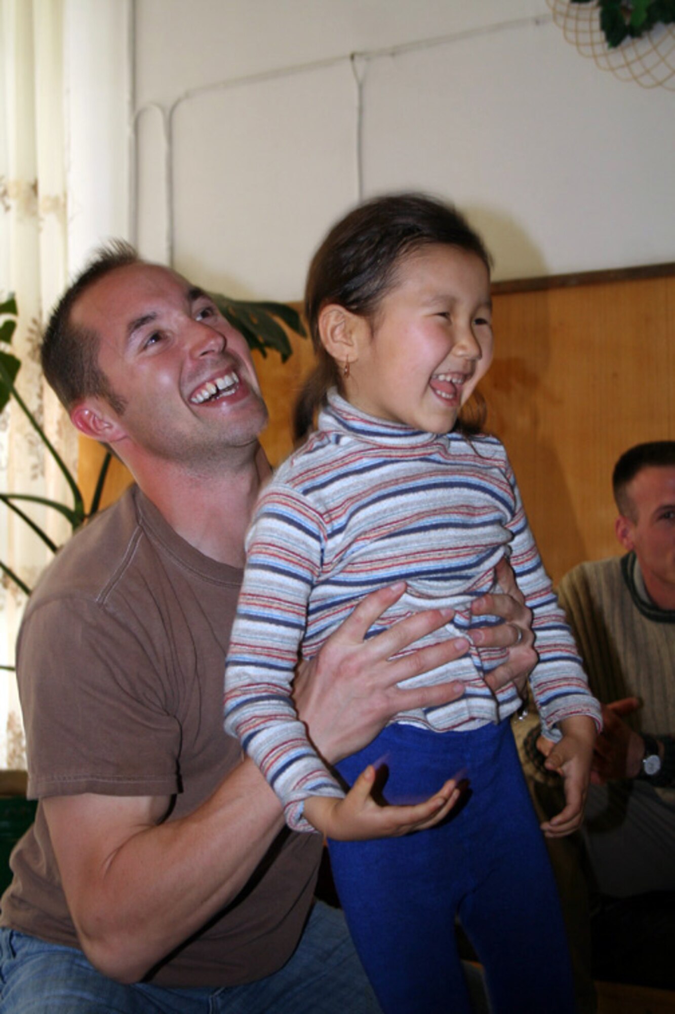 Staff Sgt. Jeremiah Christophersen plays Superman with a girl waiting to undergo heart surgery. Surgeries for eight children have been funded by the Manas Air Base Outreach Society's Children's Heart Fund this rotation. MABOS has sponsored more than 30 children since December 2003. Sergeant Christophersen is deployed to the 376th Expeditionary Civil Engineering Squadron from the 22nd CES at McConnell Air Force Base, Kan. (U.S. Air Force photo/Staff Sgt. Lara Gale)