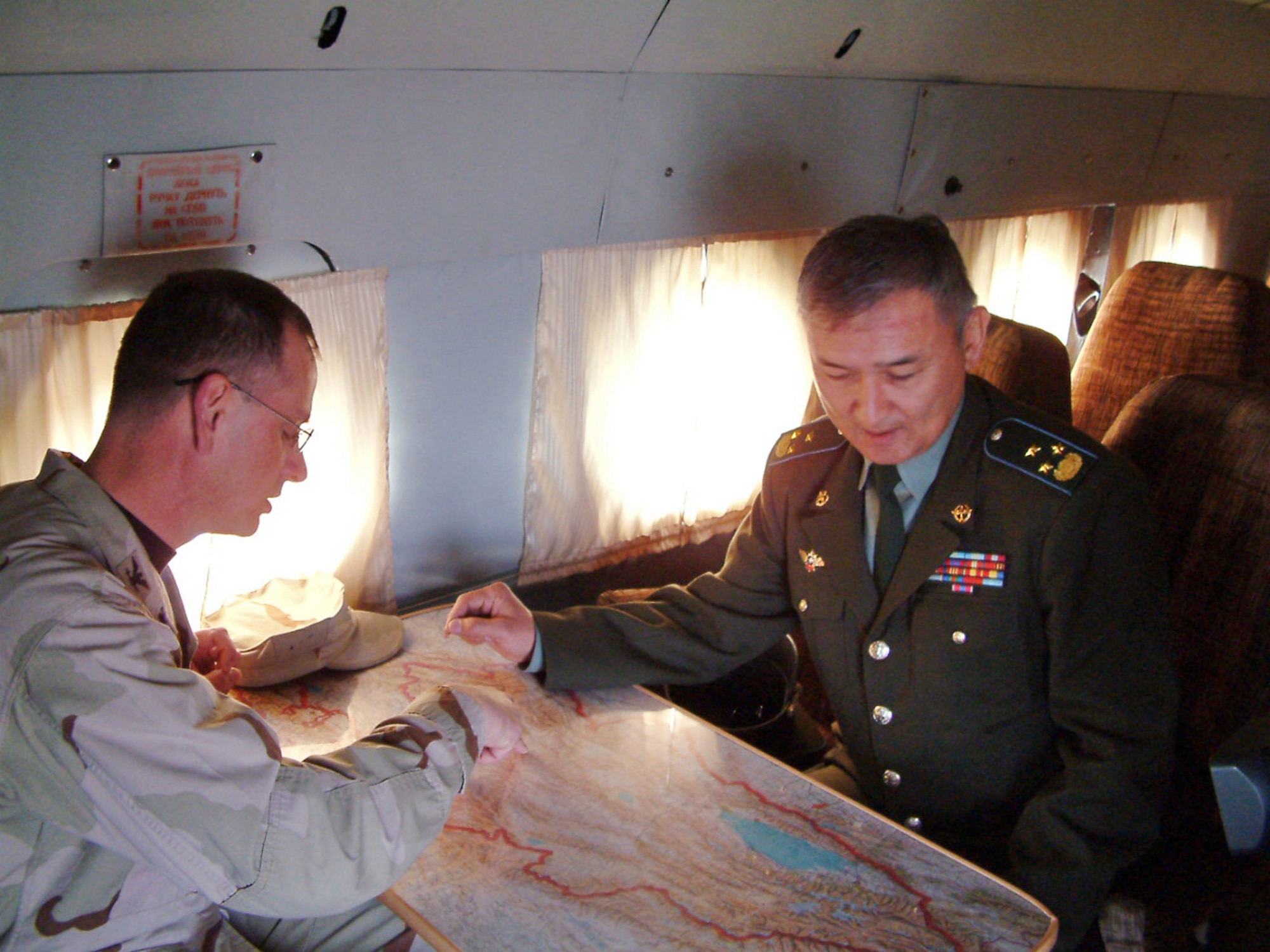 Col. Randy Kee discusses flight routes aboard a Mi-8 Hip helicopter with Kyrgyz Air Force Col. Saifutdin Azizov during a historic first U. S. military tour of Kyrgyzstan's Frunze Air Base No. 1. Colonel Kee is commander of the 376th Air Expeditionary Wing. (U.S. Air Force photo/Capt. James Bressendorff)