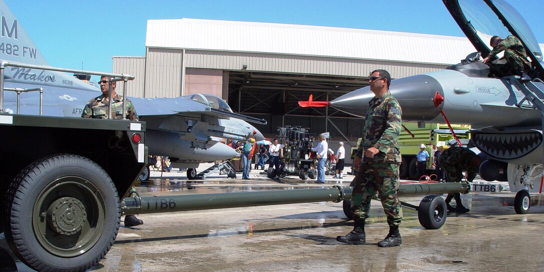 Airmen from the 482nd Fighter Wing move F-16 Fighting Falcons into position for a scene in the Warner Brothers television pilot "Mercy Reef" at Homestead Air Reserve Base, Fla., on Monday, March 27, 2006. Dozens of Airmen volunteered as extras for the show. (U.S. Air Force photo/Lisa M. Macias) 