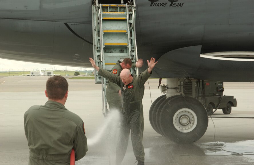 An Airman drenches C-5 crew members with a fire hose March 31 as they exit from the aircraft. The 10-member crew was returning from the final C-5 flight for the 21st Airlift Squadron. The 21st AS officially transitioned from a C-5 squadron to a C-17 squadron in a ceremony here April 3. The day also marked the squadron’s 64th anniversary. (U.S. Air Force photo by Luther Tolliver)