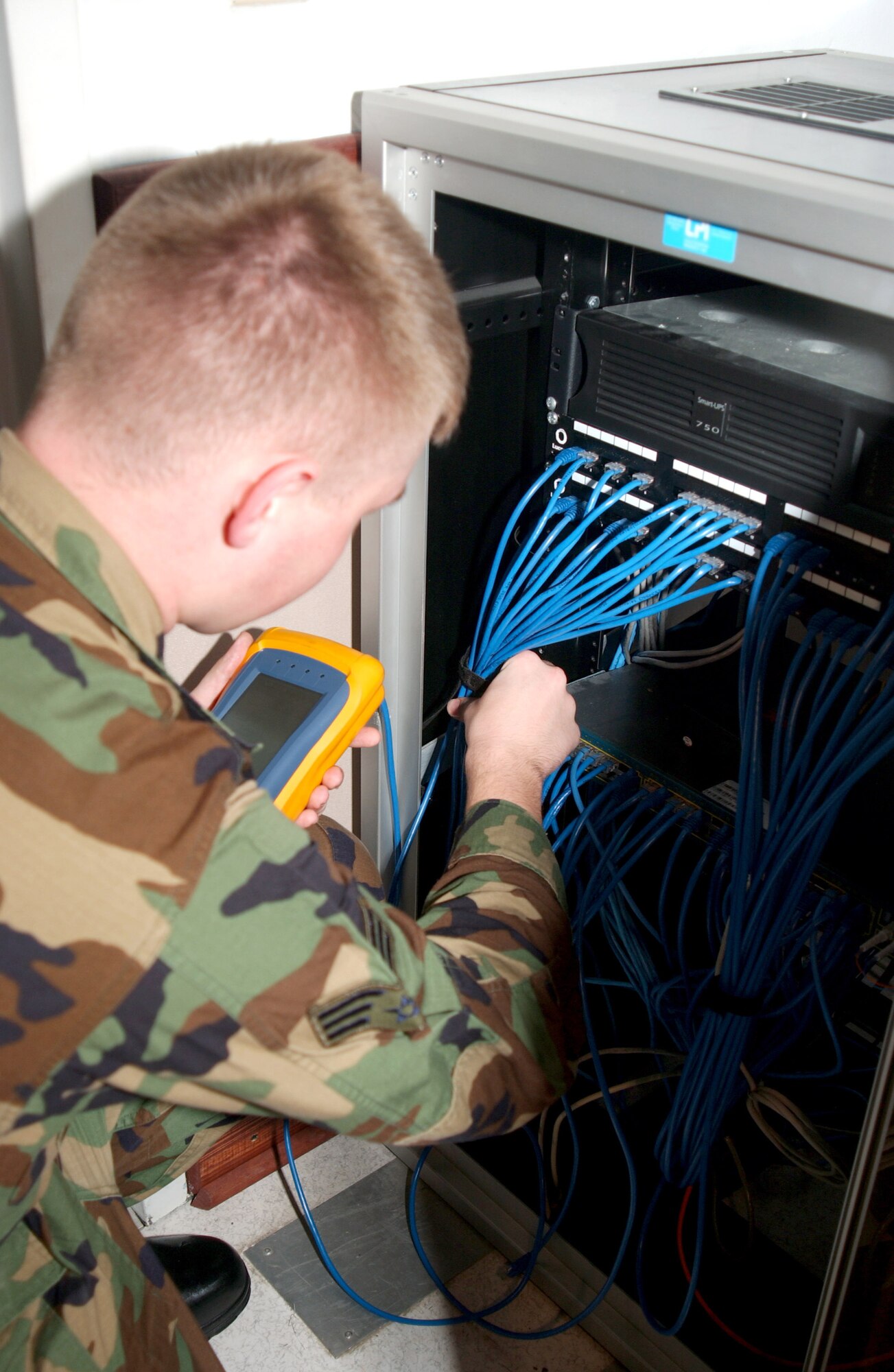 Senior Airman Marcus Wells uses a cable tester to trace category-5 network cabling between the comm closet and wall jack. (Photos by Guido Melo)