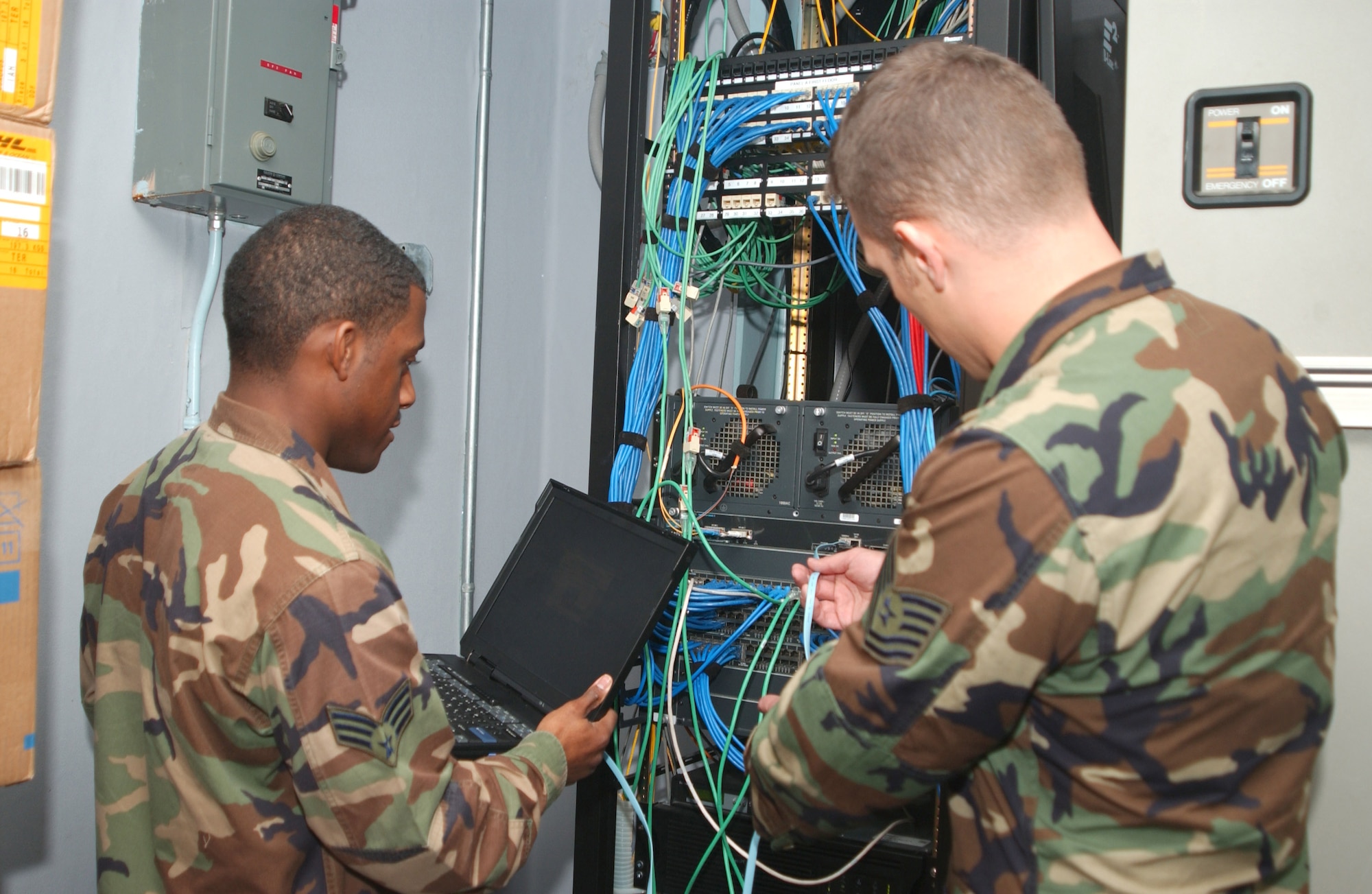 Senior Airman Theron Thompson and Tech. Sgt. William Patrick use a laptop computer to fine-tune the software configuration of a network switch.