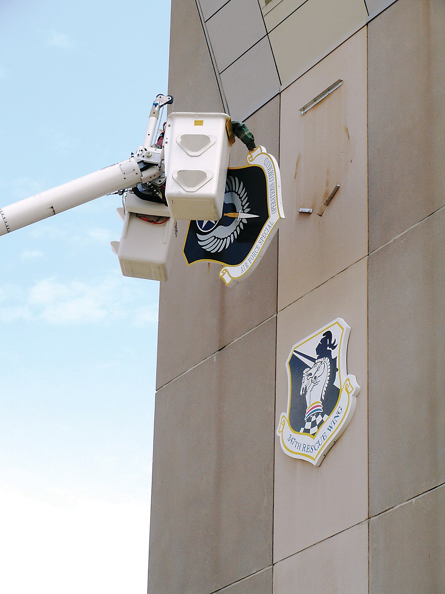 Workers from the 347th Civil Engineer Squadron remove the Air Force Special Operations Command shield Tuesday from the 347th Operations Support Squadron Air Traffic Control tower. The Air Combat Command shield was placed on the tower in preparation for the 347th Rescue Wing’s upcoming move to ACC. The wing took additional steps to convert assets to ACC Monday.
