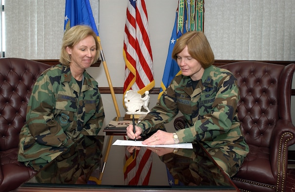 Maj. Kenny Harryman, Air Force Assistance Fund project officer here, looks on while Col. Lyn Sherlock, 60th Air Mobility Wing commander, signs her pledge for this year’s AFAF campaign. The campaign kicked off March 24 and runs through May 4. (U.S. Air Force photo by Andre Mansour)