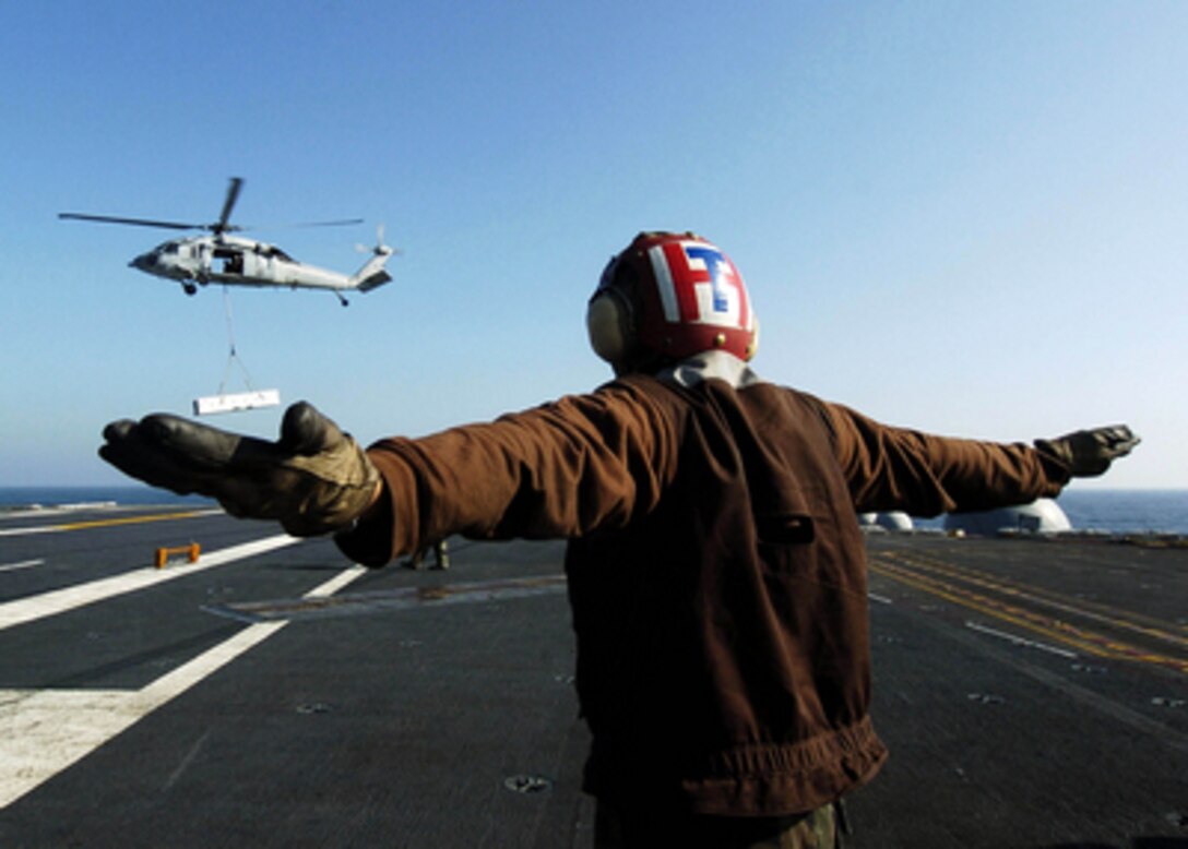 A U.S. Navy enlisted landing signalman gives the hover signal to the pilot of an MH-60S Seahawk helicopter during a vertical replenishment aboard the aircraft carrier USS Abraham Lincoln (CVN 72) on April 3, 2006. Lincoln and its embarked Carrier Air Wing 2 are operating in the Western Pacific Ocean. 