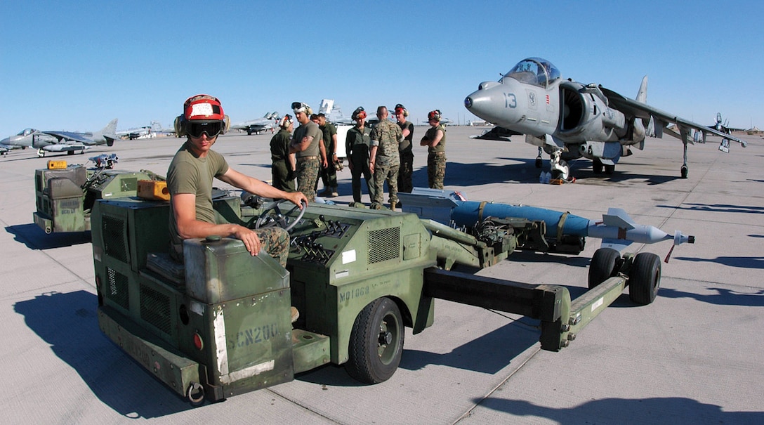 Cpl. Joey Ellis, Marine Attack Squadron 231 aviation ordnanceman, straightens a short-airfield tactical-site (SATS) loader before driving an inert version of the Guided Bomb Unit 16 (GBU-16) -- a MK-83 1,000-pound bomb modified with a Paveway II laser guidance kit -- into position under a VMA-223 AV-8B Harrier at the Combat Arms Loading Area here April 6. Other ordnancemen then attached the GBU-16 to one of the aircraft?s loading stations.