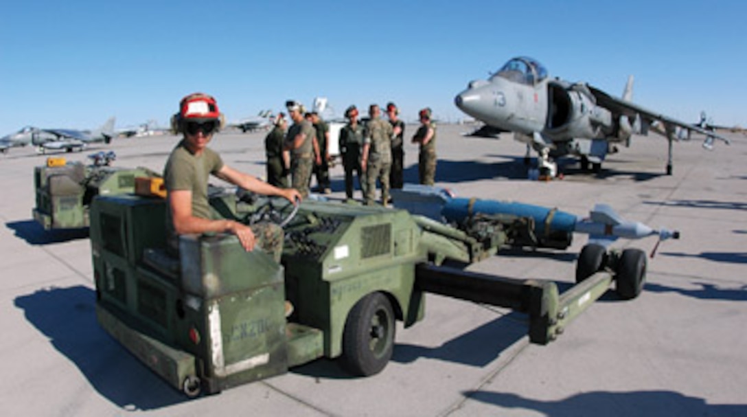 Cpl. Joey Ellis, Marine Attack Squadron 231 aviation ordnanceman, straightens a short-airfield tactical-site (SATS) loader before driving an inert version of the Guided Bomb Unit 16 (GBU-16) -- a MK-83 1,000-pound bomb modified with a Paveway II laser guidance kit -- into position under a VMA-223 AV-8B Harrier at the Combat Arms Loading Area here April 6. Other ordnancemen then attached the GBU-16 to one of the aircraft?s loading stations.