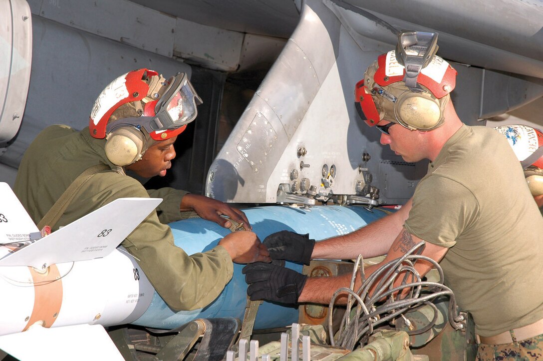 Cpl. Quan Walker (left) and Lance Cpl. Michael Bennett, both ordnancemen with Marine Attack Squadron 231, work together to quickly unstrap a GBU-16 from a short-airfield tactical-site (SATS) loader after attaching the inert bomb to VMA-223 AV-8B Harrier at the Combat Arms Loading Area here April 6.