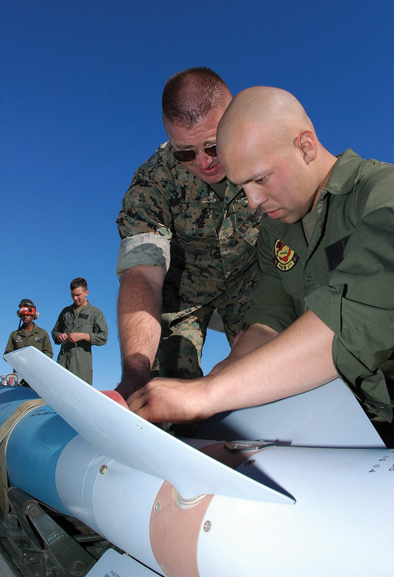 Master Gunnery Sgt. Ronnie Jones, Jr., Marine Aviation Weapons and Tactics Squadron 1 ordnance chief, teaches Lance Cpl. Francisco Iniguez, Marine Attack Squadron 211 aviation ordnanceman, to thread a thermal battery cable into a GBU-16 at the Combat Arms Loading Area here April 6. This is one step in Preload Accessory Suspension Equipment loading.