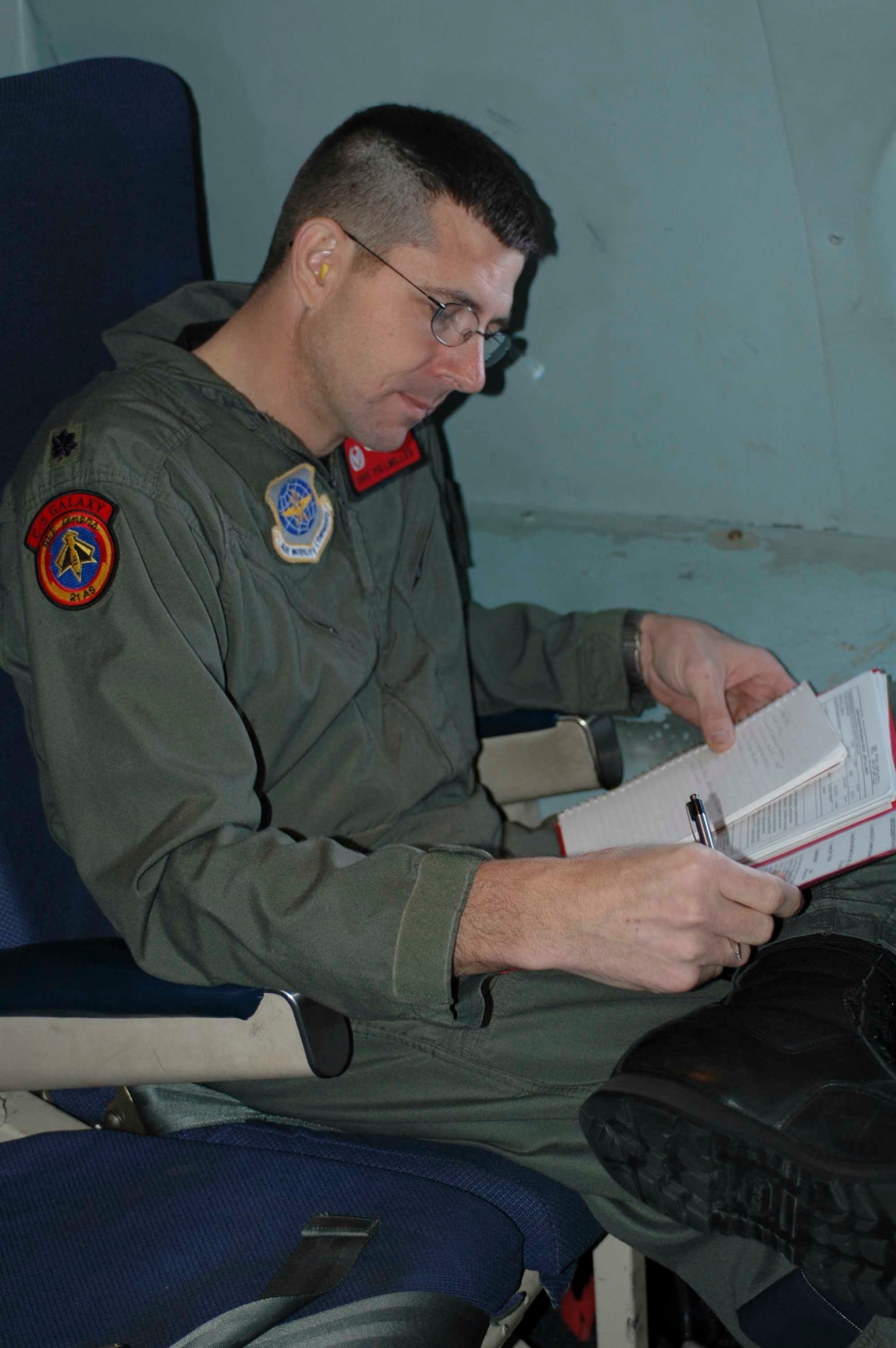 Lt. Col. David Pollmiller, 21st Airlift Squadron commander, reviews annual reports and awards while aboard for the squadron's final C-5 flight March 31. The 21st AS officially transitioned from a C-5 squadron to a C-17 squadron in a ceremony here April 3, which was also the squadron’s 64th anniversary. (U.S. Air Force photo by Airman 1st Class Tiffany Low)