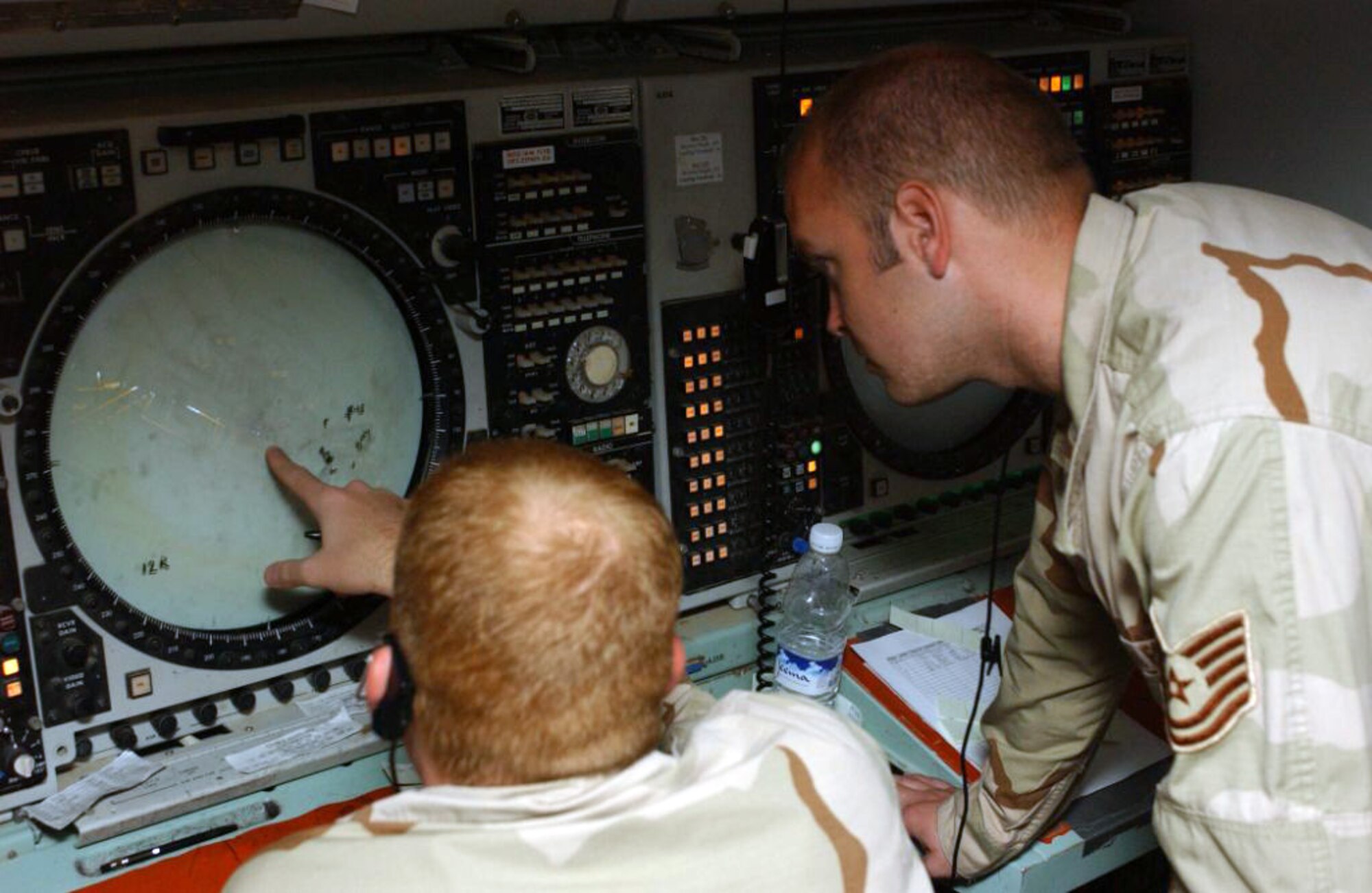 Staff Sgt. Scott Williams (left) goes over aircraft positions before turning over the radar to Tech. Sgt. Andrew Peters at the Ali Base area control center in Iraq. (U.S. Air Force photo/Master Sgt. Jon Hanson) 
