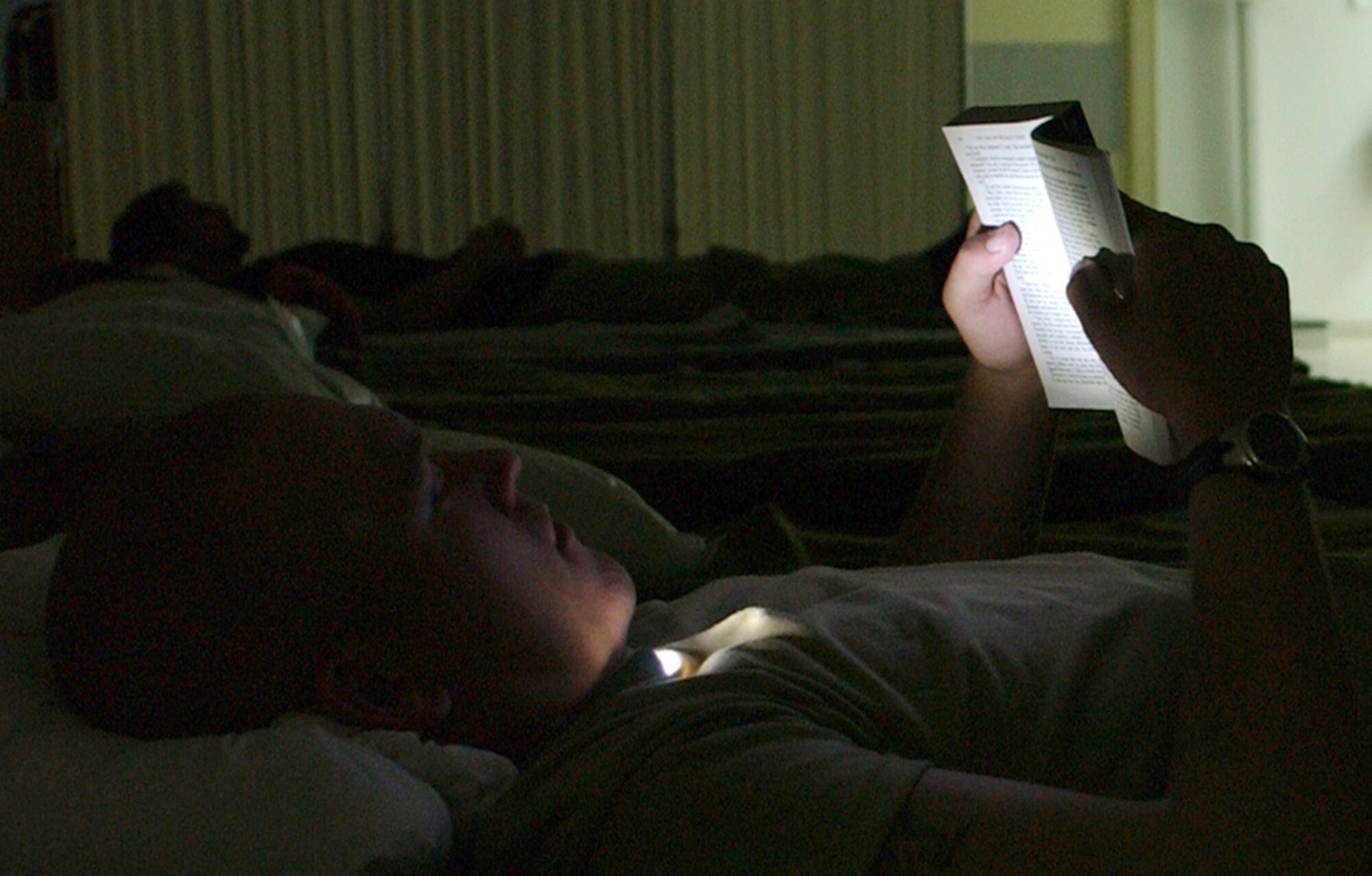Army Spc. Andrew Elsnel reads by flashlight Monday, April 3, 2006, at the Contingency Aeromedical Staging Facility at Balad Air Base while he waits for his flight out of Iraq. (U.S. Air Force photo/Staff Sgt. Robert Wollenberg)                     