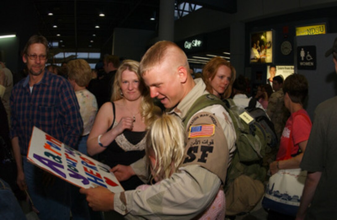 Air Force Staff Sgt. Aaron D. Giere reads a hand-lettered sign as friends and family welcome him home at the Hector International Airport, Fargo, N.D., on April 6, 2006. Giere is returning from a deployment to Iraq with the 119th Security Forces Squadron. 