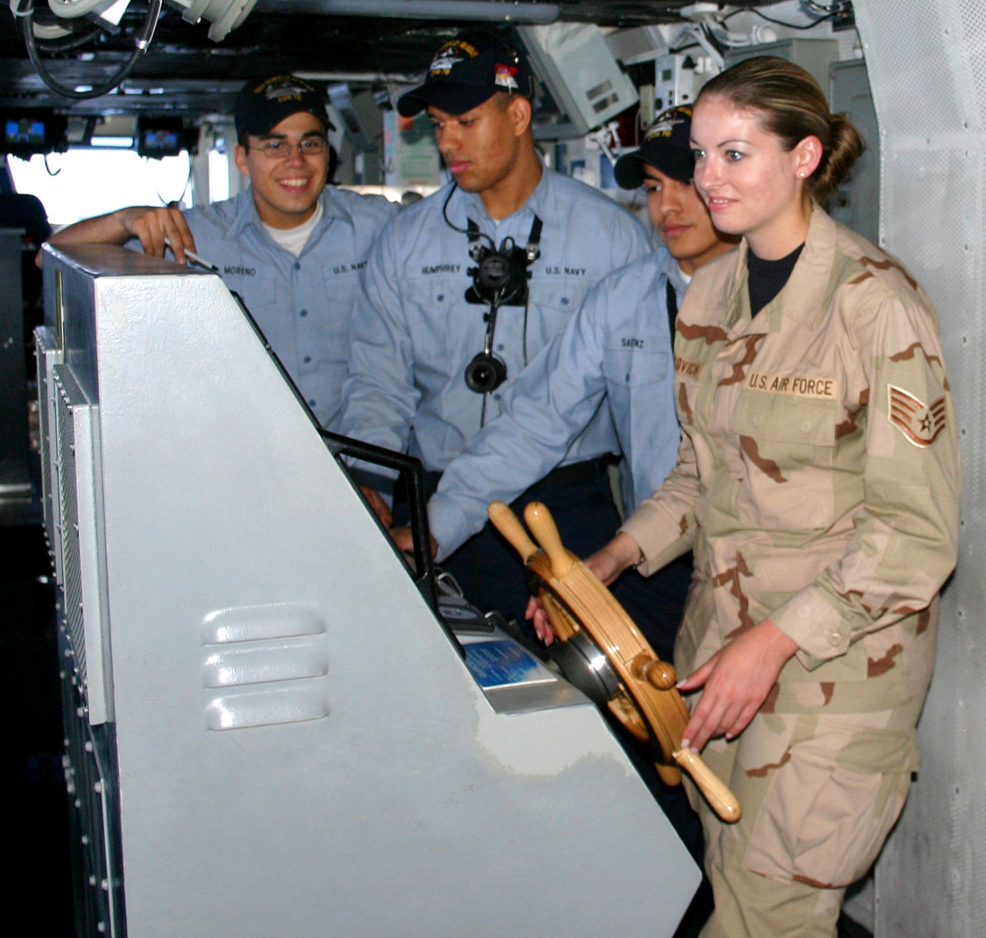 Sailors aboard the USS Ronald Reagan help Staff Sgt. Melissa Koskovich steer the ship 30 degrees to starboard during an orientation tour Thursday, March 30, 2006. Ten Airmen from Southwest Asia came aboard the ship for a two-day visit aimed at fostering joint relations throughout the area of operations. (U.S. Air Force photo/Master Sgt. Bruce Morrow)