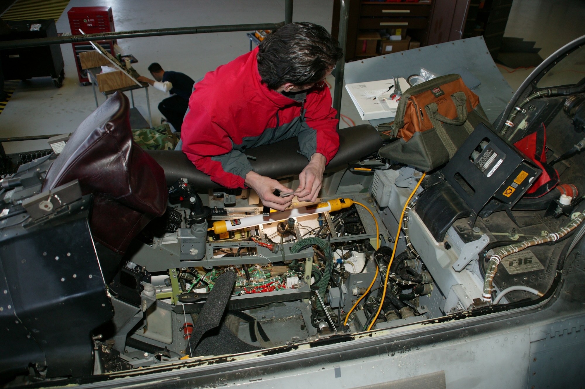 Toby Begendorf, Lockheed Martin contract worker, installs new wiring March 22 on a Shaw F-16 as part of the onboard oxygen generating system.