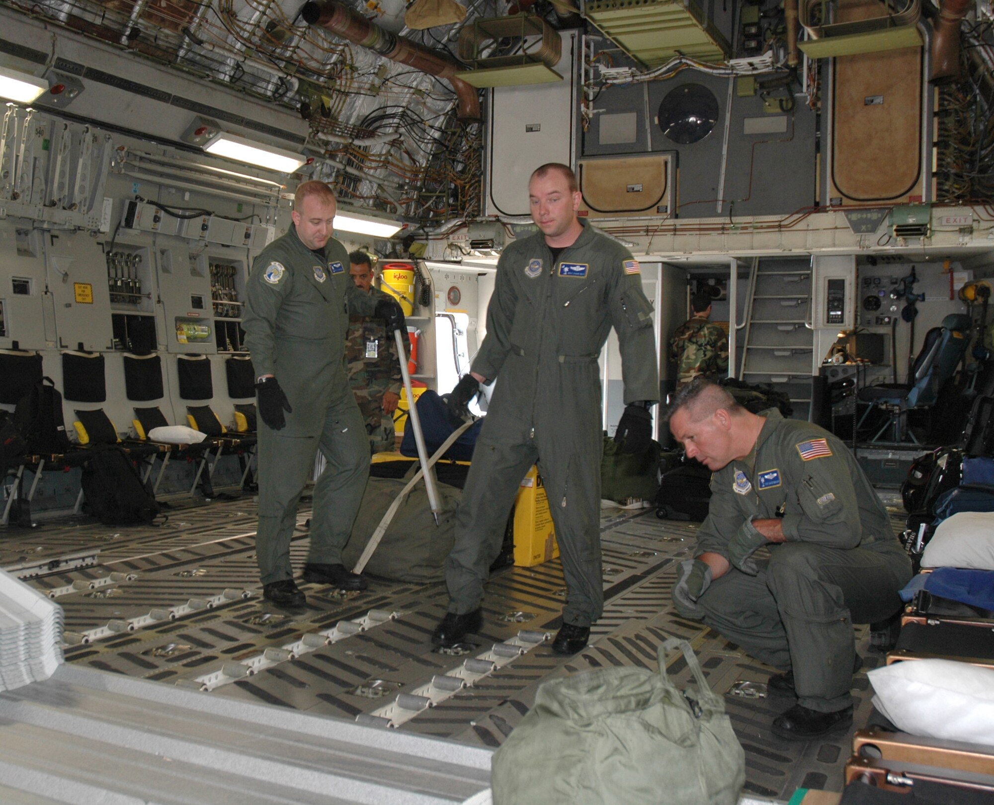Staff Sgt. Jason Hoffman (left), Master Sgt. Shawn Delp (center) and Tech. Sgt. David Benson (right), reserve loadmasters with the 300th Airlift Squadron, Charleston AFB, S.C., check cargo as it is being loaded on a C-17 Globemaster III during a recent training mission.  (Photo by 1st Lt. Wayne Capps, USAFR)