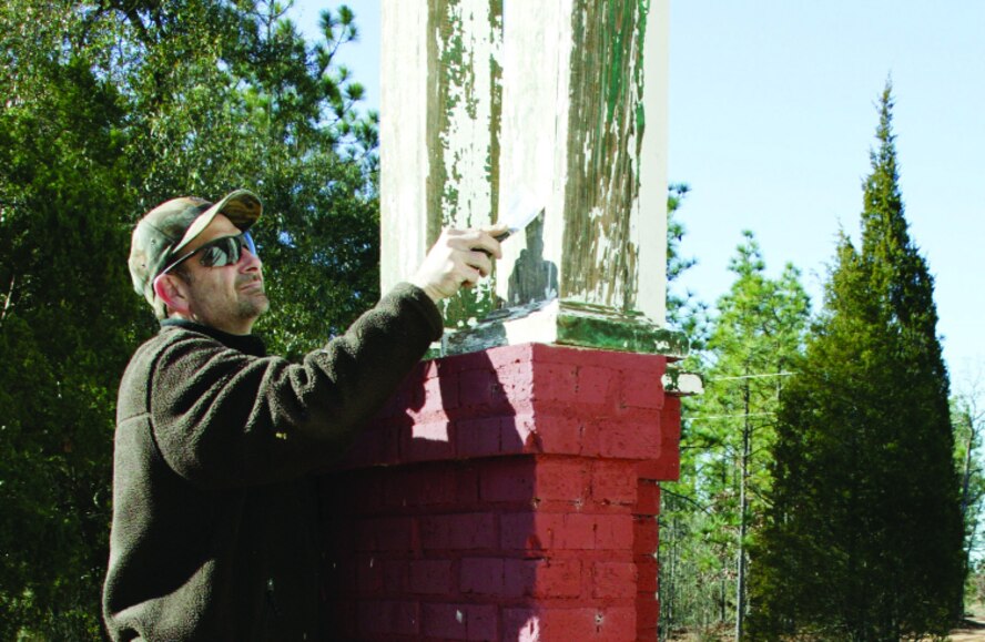David Davis, 20th CES wildlife biologist and natural resource planner, scrapes paint off the Rosemary House in preparation for restoration.