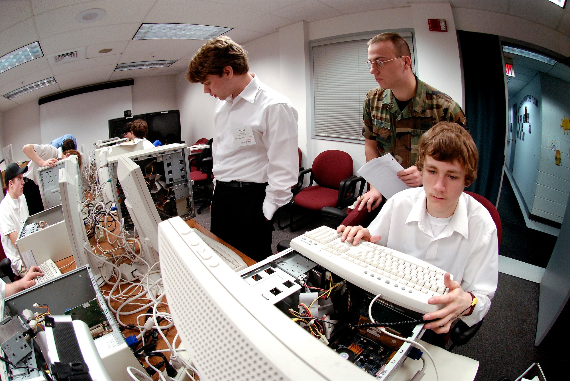 Staff Sgt. Ryan Davis monitors the SkillsUSA computer maintenance competition, hosted by the Vermont Air National Guard. Waiting for his computer to reboot is Aaron Edwards, an 11th grader at the Center for Technology in Essex, Vt. Craig Beyette troubleshoots his computer. He is an 11th grader at Stafford Technical Center in Rutland, Vt. Sergeant Davis is a computer network, switching and cryptographic specialist with the 158th Communications Flight in South Burlington, Vt. (U.S. Air Force photo/Master Sgt. Rob Trubia)