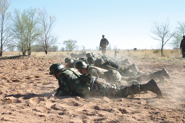 CANNON AIR FORCE BASE, N.M. -- Airman 1st Class Ryan Sollars, 27th Equipment Maintenance Squadron, high-crawls in a line of his teammates while one of their 27th Security Forces Squadron instructors, Senior Airman Brian Flanagan, makes sure nobody raises too high. The high-crawls were part of a Warrior Week training course held here Monday through today. (U.S. Air Force photo by Airman Thomas Trower)
