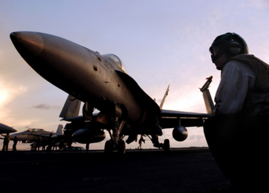 A U.S. Navy flight deck crewman watches as an F/A-18C Hornet aircraft makes a turn on the flight deck aboard the USS Abraham Lincoln (CVN 72) on April 14, 2006. Lincoln and Carrier Air Wing 2 are operating in the South China Sea. 