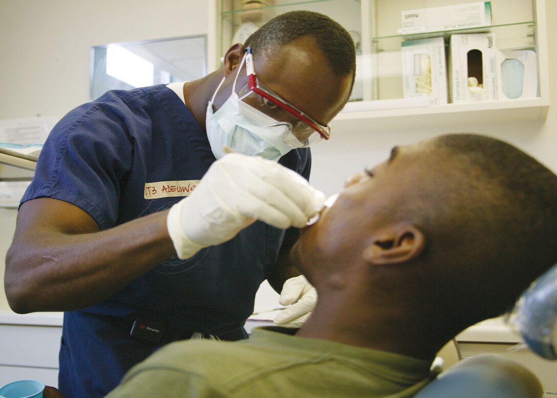 Petty Officer Third Class Solomon Adolowo provides care to a recruit at the Branch Dental Clinic April 13. Adolowo came to the United States from Africa on an acedemic scholarship, but after the rigors of school life caught up to him, he sought out a career in the Navy.