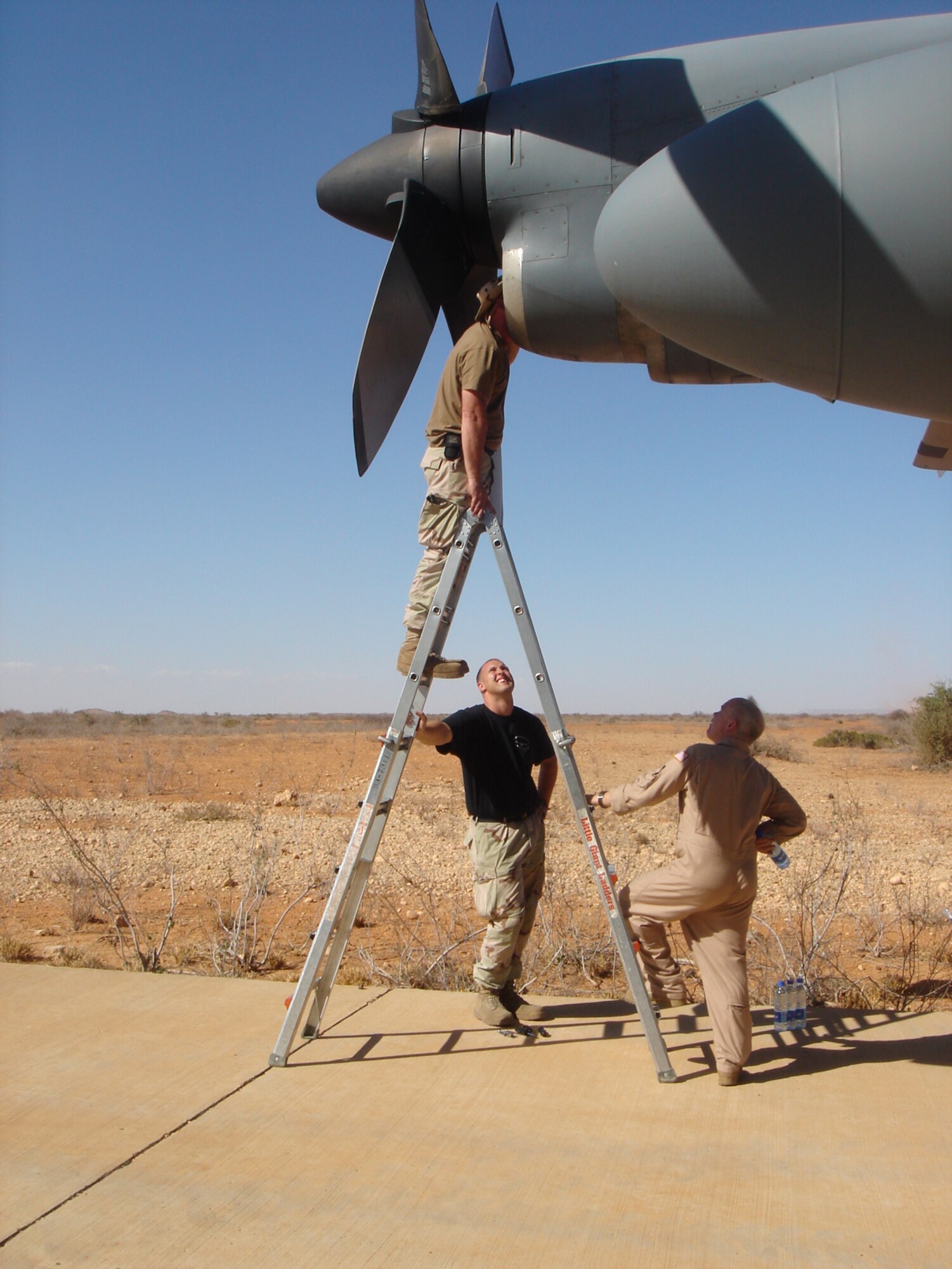 Master Sgt. Steven Ashley, 746th Expeditionary Airlift Squadron, examines an engine that broke on a C-130 Hercules mission to the Horn of Africa. Senior Airman Christopher Sutton (black shirt), 746th Aircraft Maintenance Unit crew chief, and Senior Master Sgt. David Bright, 746th EAS flight engineer, watch from below. (U.S. Air Force photo/Maj. Ann Peru Knabe)                               