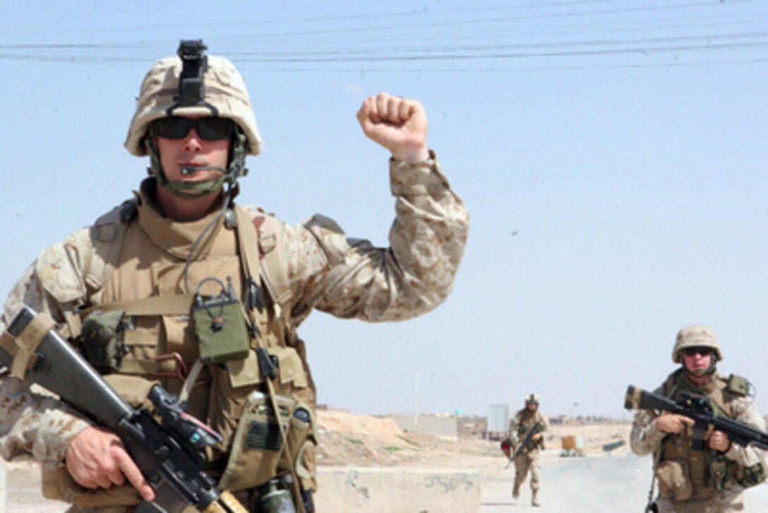 U.S. Marine Corps Cpl. Adam A. Anderson signals to his squad to halt during a presence patrol in Karabilah in the Al Anbar province of Iraq on April 12, 2006. Anderson is assigned to 3rd Squad, 1st Platoon, Charlie Company, 1st Battalion, 7th Marine Regiment. 