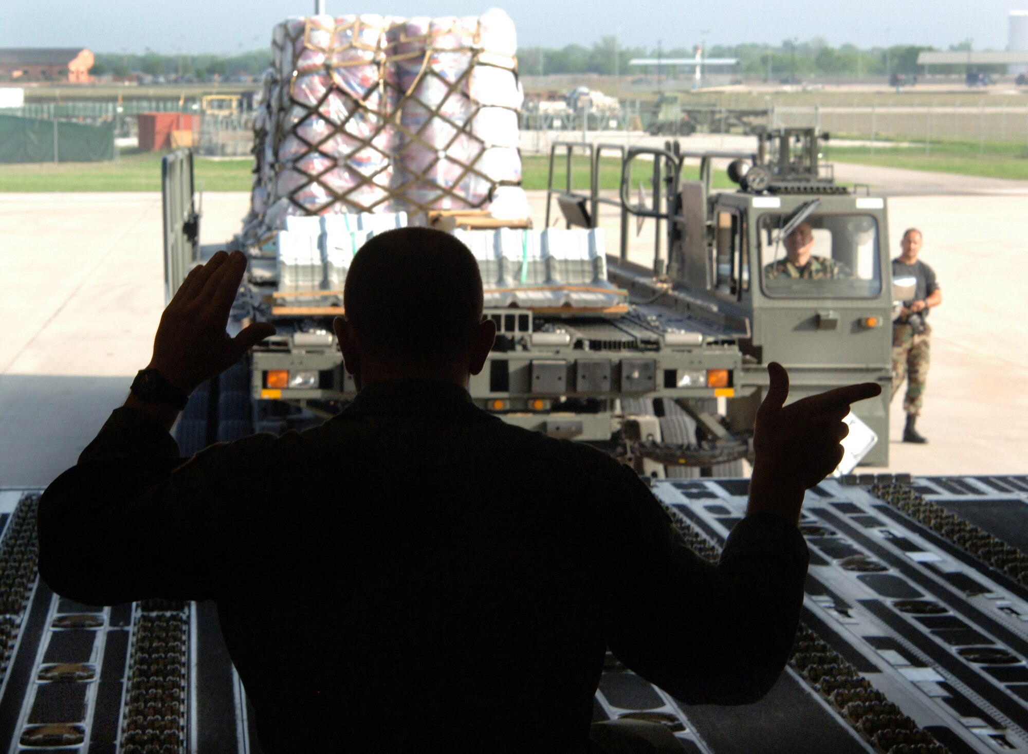 Master Sgt. Shawn Delp signals the driver to line up cargo for loading in preparation for a mission to Saint Lucia Friday, April 7, 2006. The aircrew was delivering construction materials and Reserve civil engineers who are building an operations center and barracks for the police force in support of Saint Lucia's counter-drug operations.  Sergeant Delp is with the 300th Airlift Squadron at Charleston Air Force Base, S.C. (U.S. Air Force photo/Tech. Sgt. Larry A. Simmons)